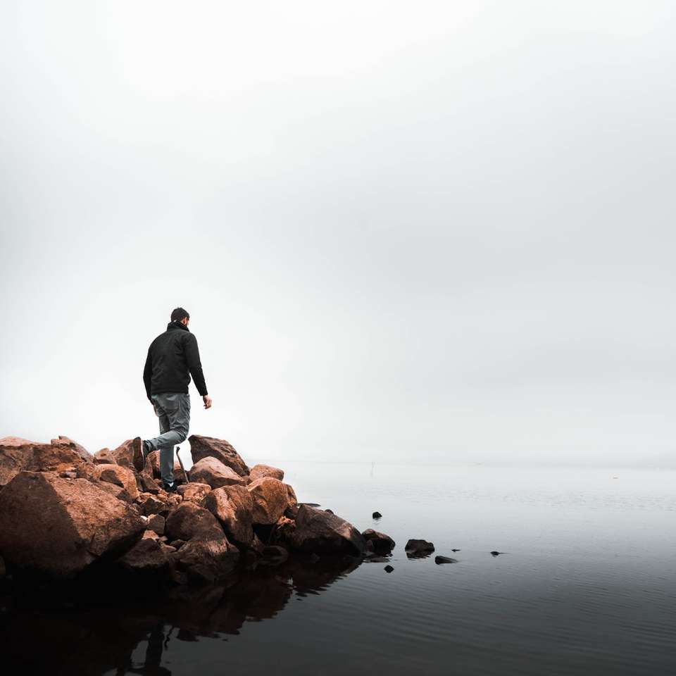 άντρας περπατώντας πάνω σε βράχια δίπλα στην παραλία online παζλ