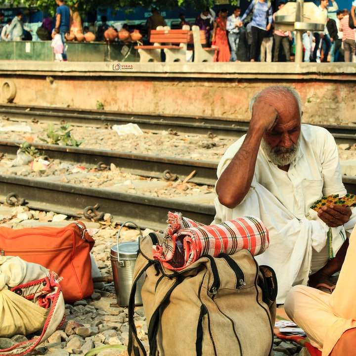 Hombre sentado en la vía del tren durante el día puzzle deslizante online