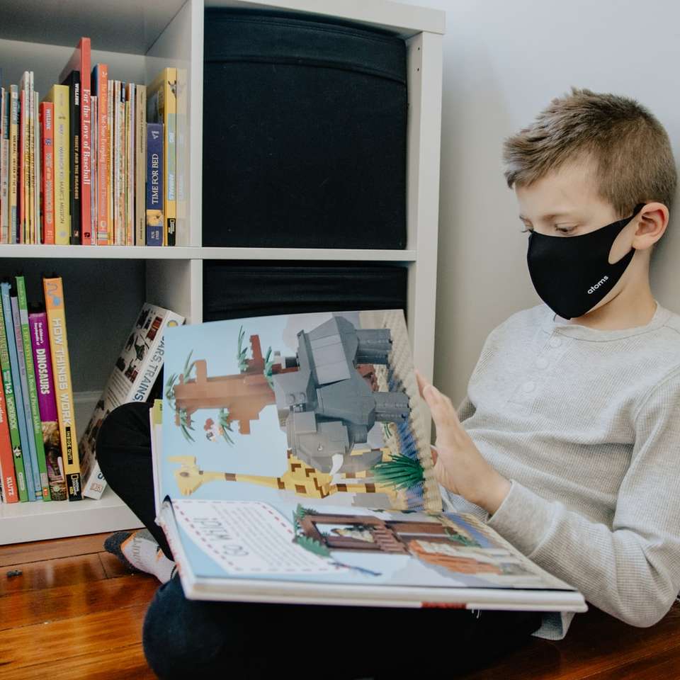 Boy looking through lego book wearing a mask sliding puzzle online