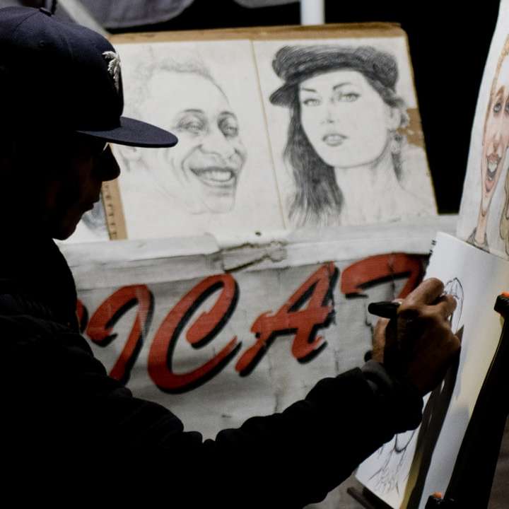 Hombre vestido con gorra sentado mientras hace bocetos de retratos rompecabezas en línea