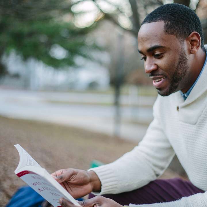 homem vestindo suéter branco enquanto lê um livro puzzle online