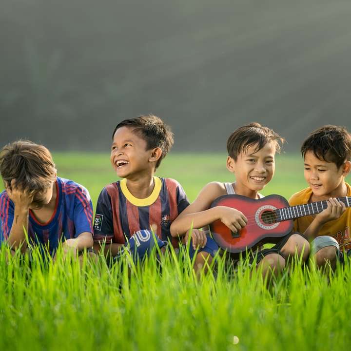 quatre garçons riant et assis sur l'herbe pendant la journée puzzle en ligne