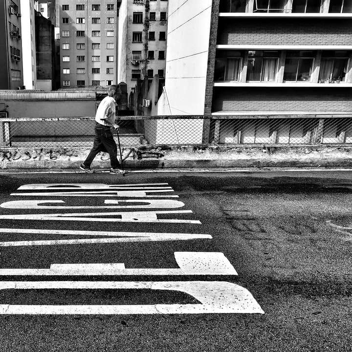 fotografia in scala di grigi di una persona che cammina accanto alla strada asfaltata puzzle scorrevole online