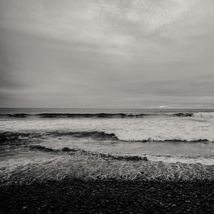 vagues de l'océan s'écraser sur le rivage sous un ciel nuageux puzzle en ligne