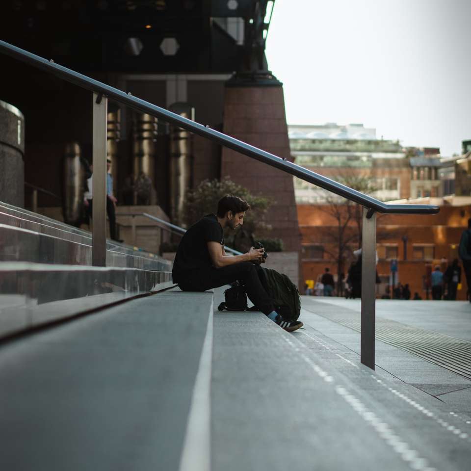 Mann sitzt auf Betontreppe nahe Straße während des Tages Schiebepuzzle online