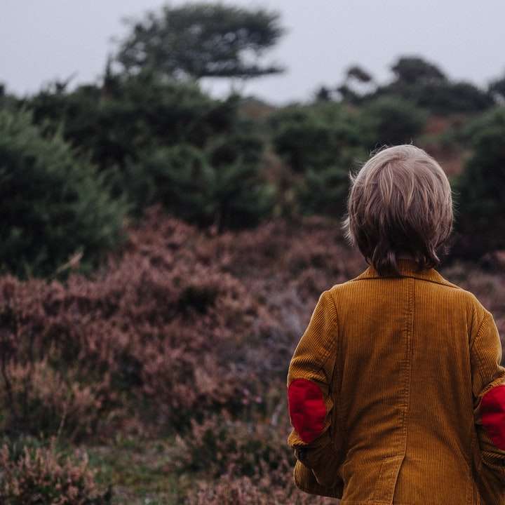 pojke som bär brun kappa som ser på träd Pussel online