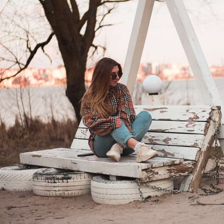 жена в сини дънкови дънки, седнала на бяла дървена пейка плъзгащ се пъзел онлайн