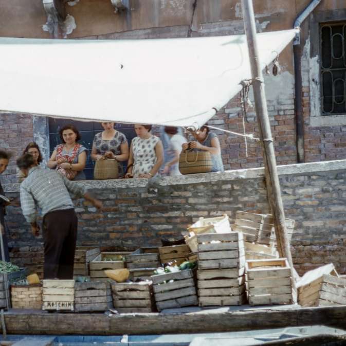 Mann und Frau auf dem Boot, das Früchte in der Kiste verkauft Online-Puzzle