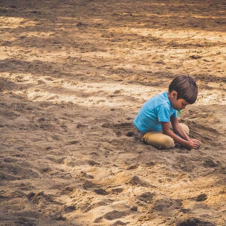 boy playing on sand during daytime sliding puzzle online