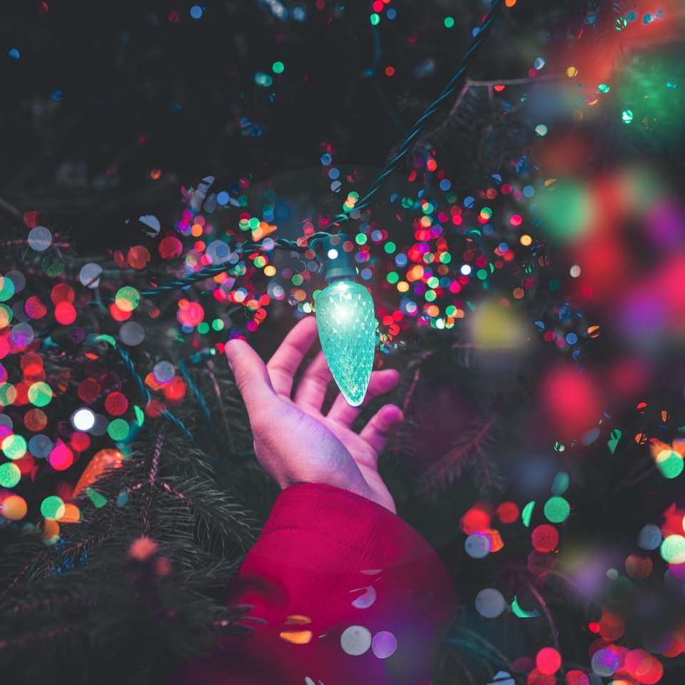 bokeh photography of person holding green string light sliding puzzle online