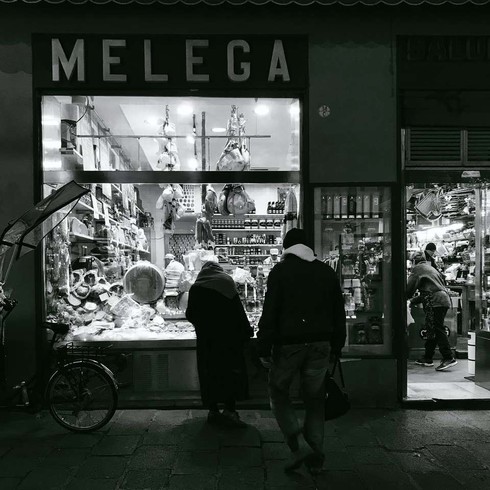 Foto en escala de grises de dos personas de pie en la tienda Melega puzzle deslizante online