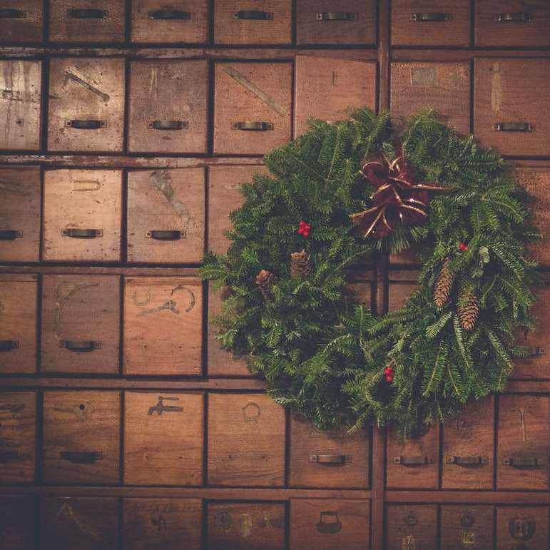 Couronne de Noël pomme de pin verte et brune sur des tiroirs en bois puzzle coulissant en ligne