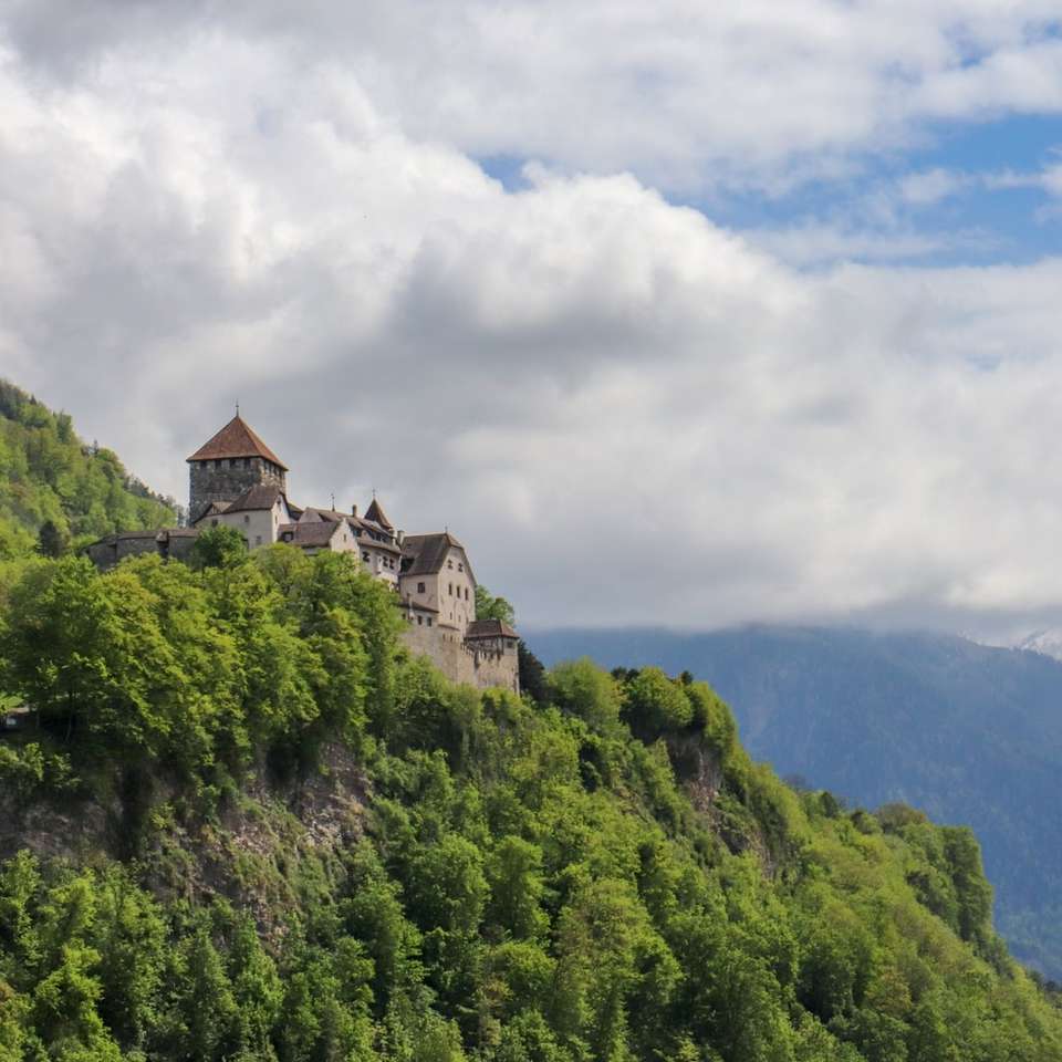 edificio in cemento bianco e marrone in cima a una montagna verde puzzle online