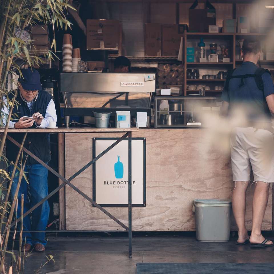 Hombre apoyado en la mesa en frente de la tienda de café puzzle deslizante online