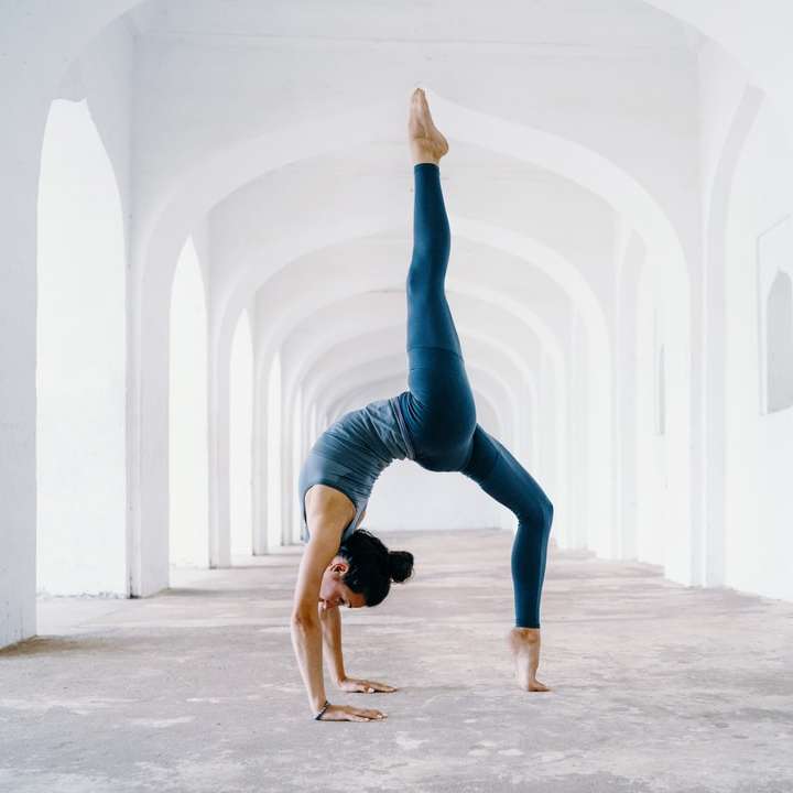 Femme en leggings bleus et débardeur noir faisant du yoga puzzle coulissant en ligne