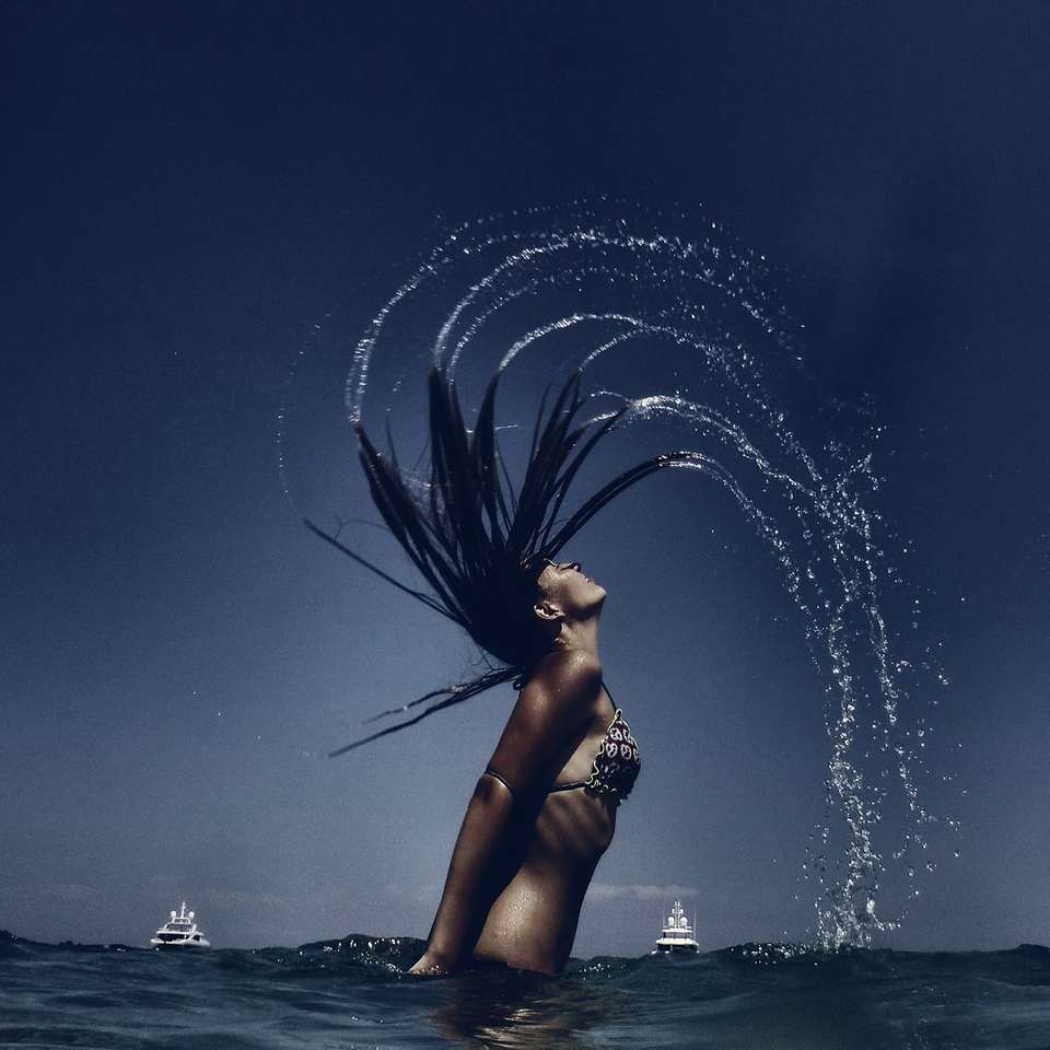 kobieta przerzucając włosy podczas moczenia w zbiorniku wodnym puzzle online