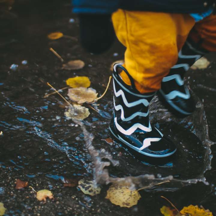 Niño vistiendo botas de lluvia en blanco y negro de pie en el cuerpo puzzle deslizante online