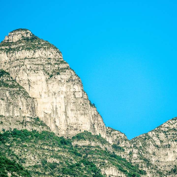 昼間の青い空の下の灰色の岩山 オンラインパズル