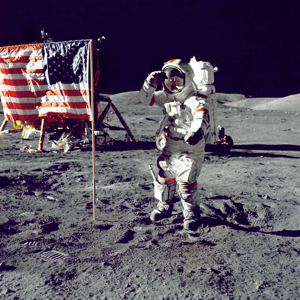 astronauta stojący na Księżycu obok flagi USA puzzle online