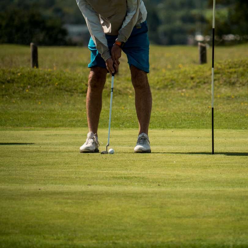 мъж в бяла риза и сини шорти, играещ голф онлайн пъзел