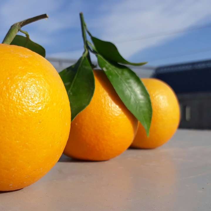 Tres frutas naranjas redondas sobre mesa gris puzzle deslizante online