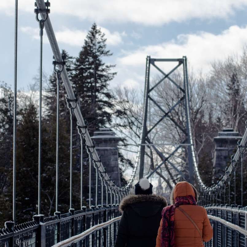 dwie osoby idące po szarym moście wiszącym puzzle online