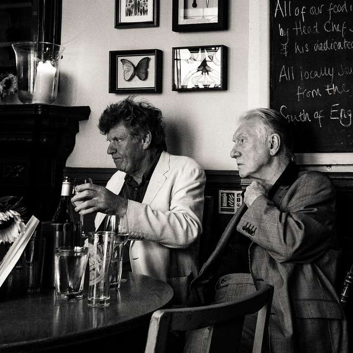 grijswaardenfoto van drie man zittend naast tafel schuifpuzzel online