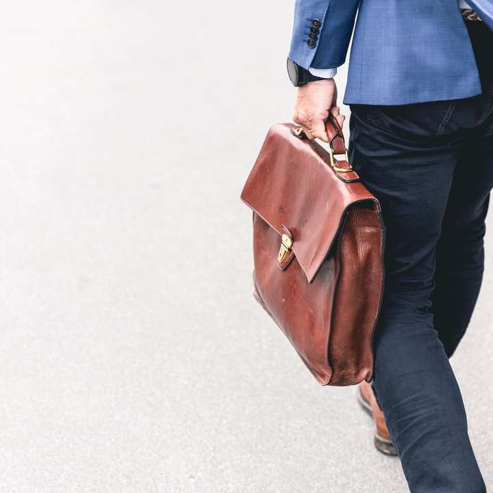 човек, разхождащ се, държащ кафява кожена чанта плъзгащ се пъзел онлайн