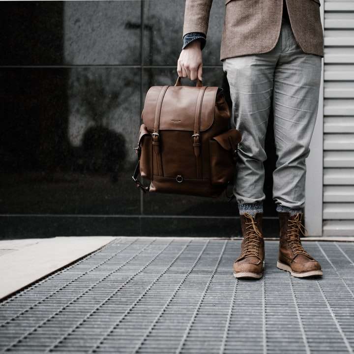 човек, държащ кафява кожена чанта плъзгащ се пъзел онлайн