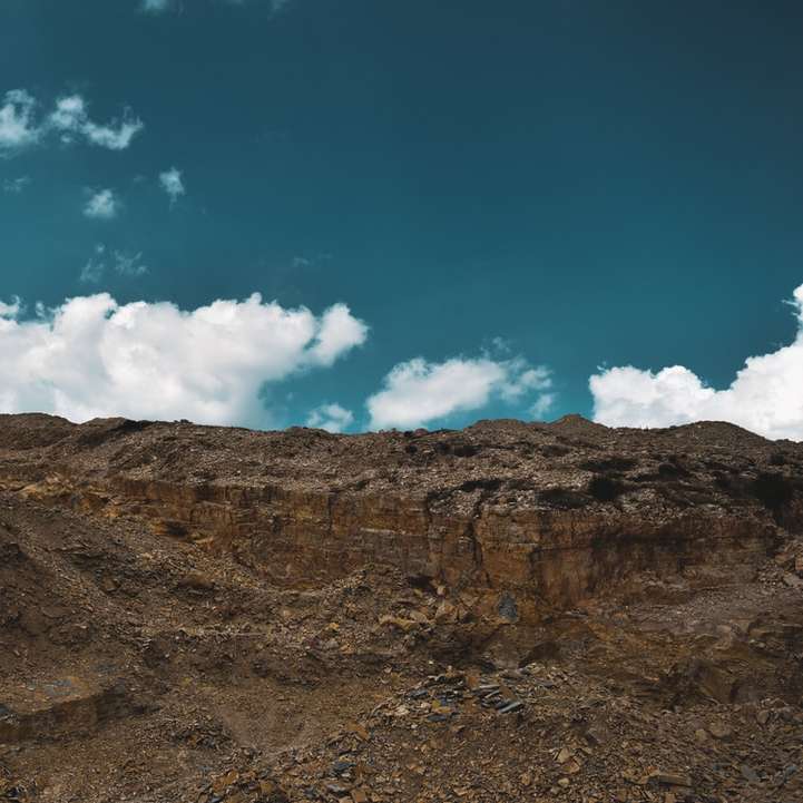 bruine rotsachtige berg onder blauwe lucht en witte wolken schuifpuzzel online