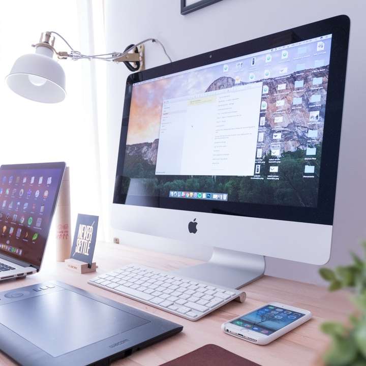 stříbrný iMac poblíž iPhone na hnědém dřevěném stole online puzzle