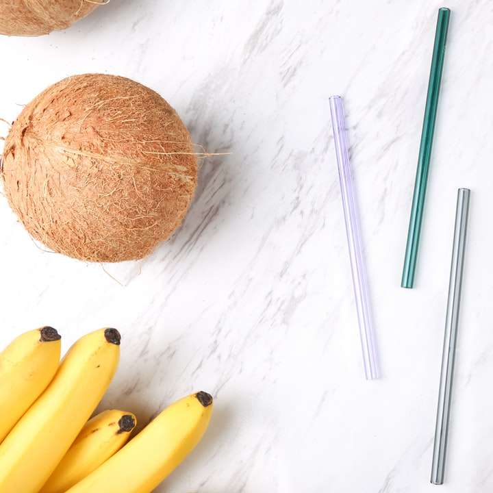 vier verschiedenfarbige Strohhalme neben Kokosnuss, Bananen Schiebepuzzle online