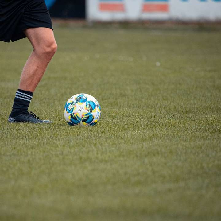 Человек в черных шортах и ​​бело-синем футбольном мяче раздвижная головоломка онлайн