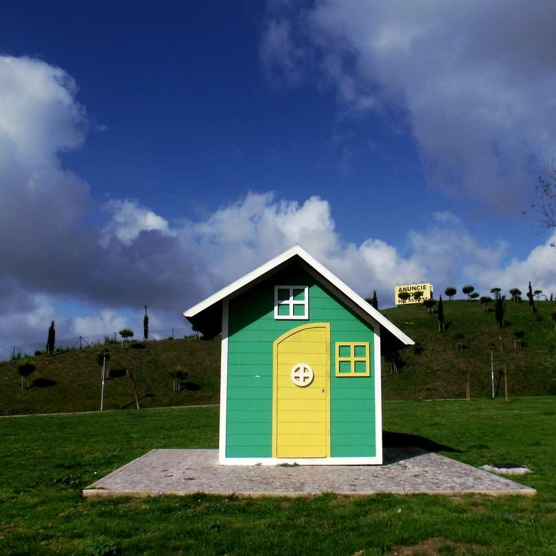 casa de madeira verde e branca em campo de grama verde puzzle deslizante online