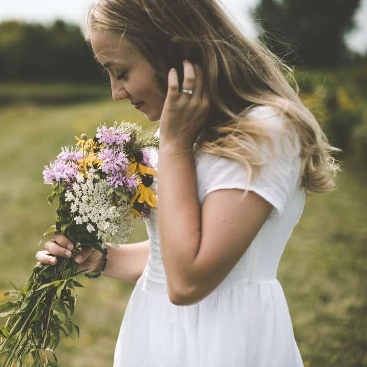 γυναίκα που φοράει άσπρο πουκάμισο κρατώντας λουλούδι μυρίζοντας online παζλ