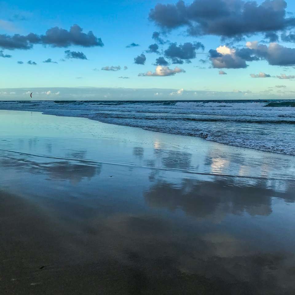 havsvågor som kraschar på stranden under blå och vit molnig himmel glidande pussel online
