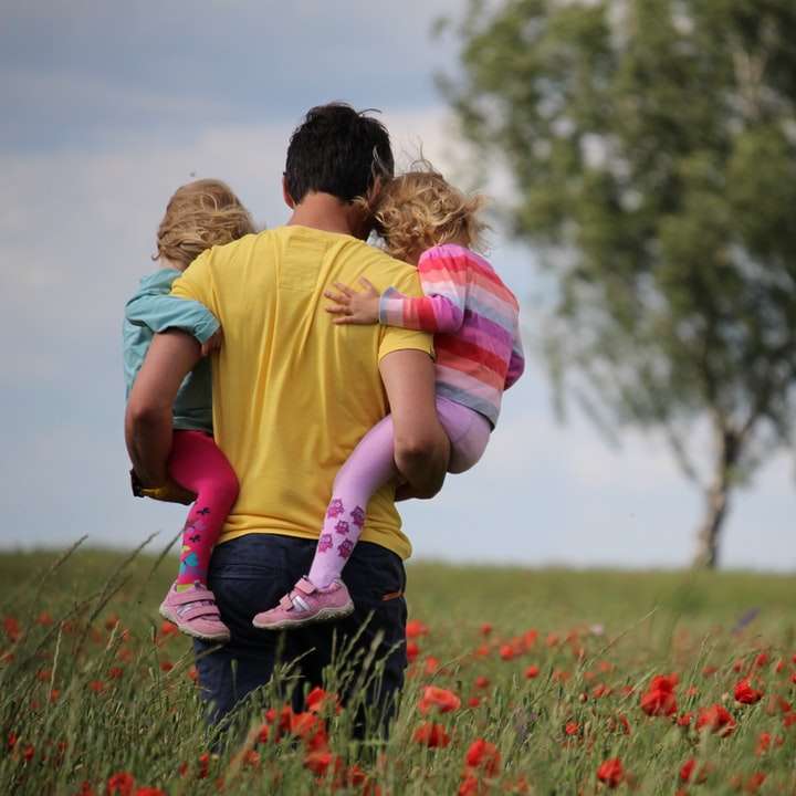man carrying to girls on field of red petaled flower online puzzle
