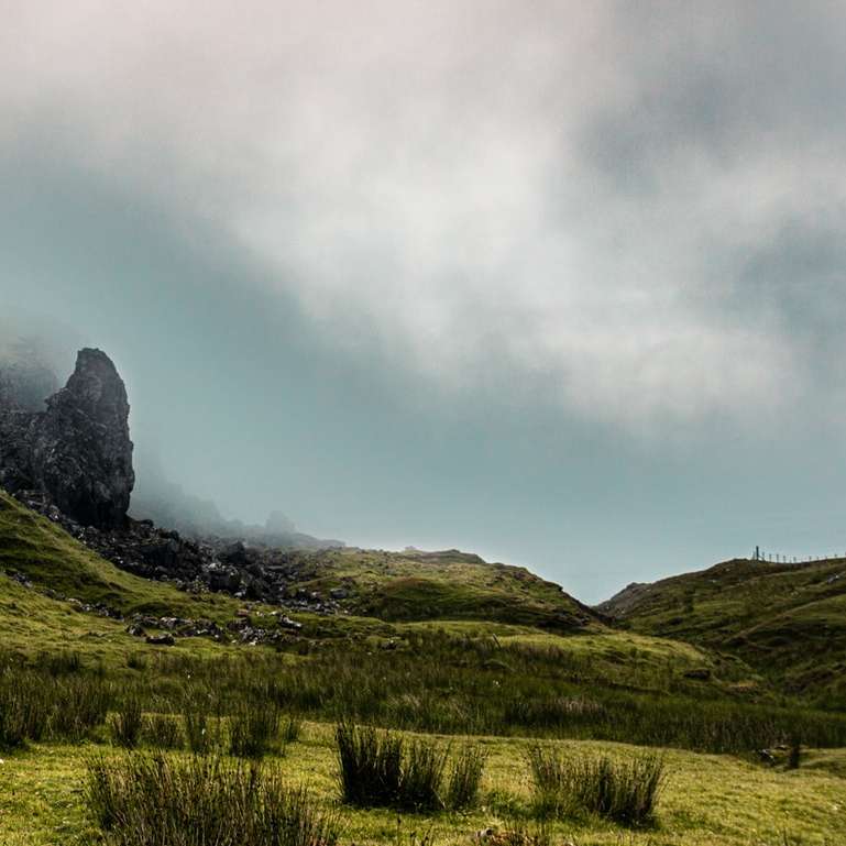 zielona trawa pole w pobliżu góry pod pochmurnym niebem puzzle przesuwne online
