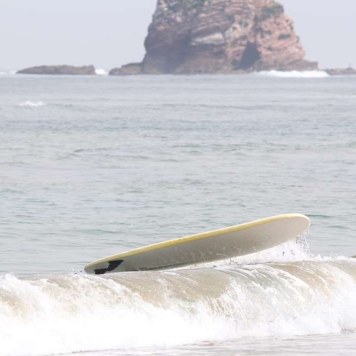 Tabla de surf amarilla en el mar durante el día rompecabezas en línea