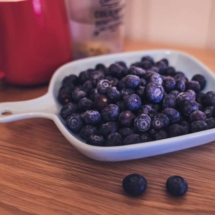 Frutti di Huckleberry in una ciotola con manico sul tavolo puzzle online