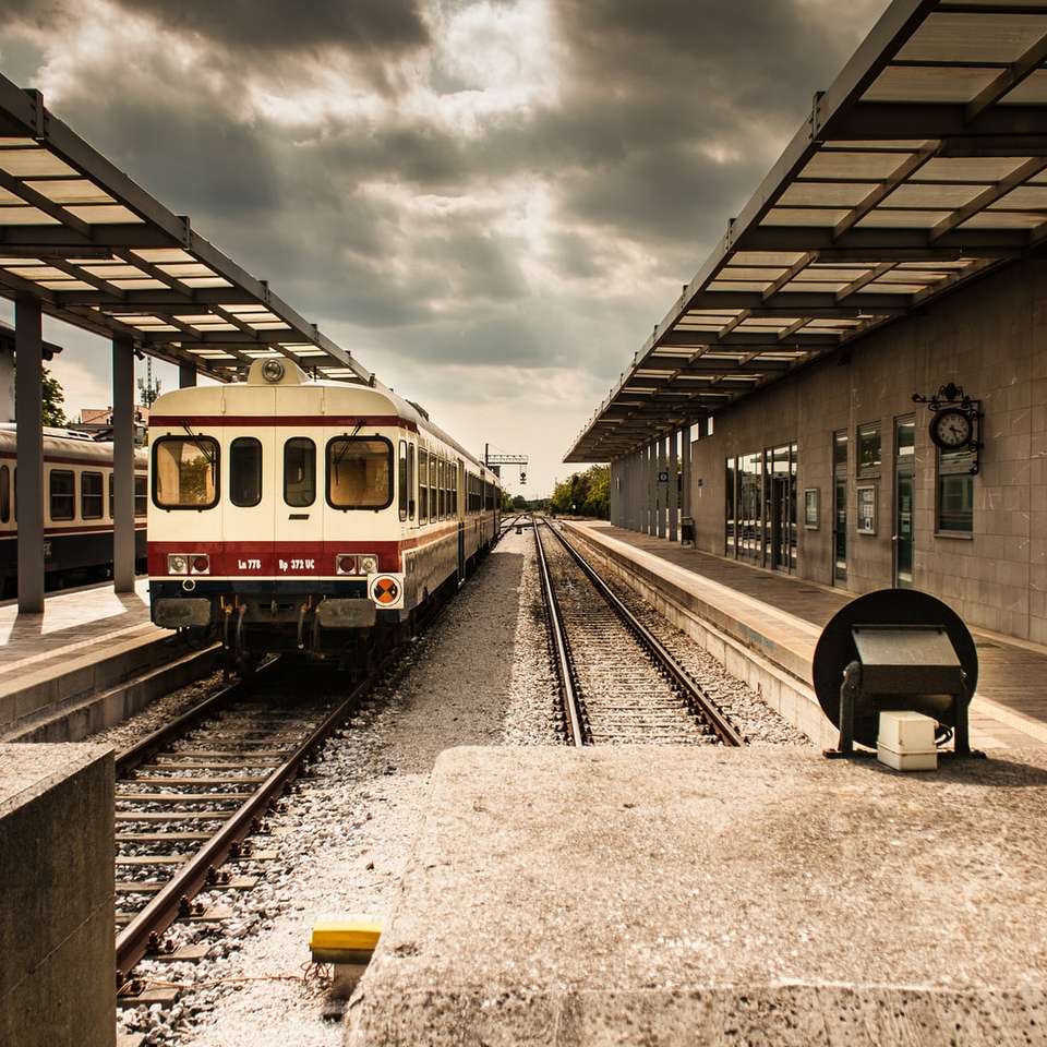φωτογραφία του λευκού και κόκκινου σιδηροδρομικού σταθμού κάτω από τον γκρίζο συννεφιασμένο ουρανό online παζλ