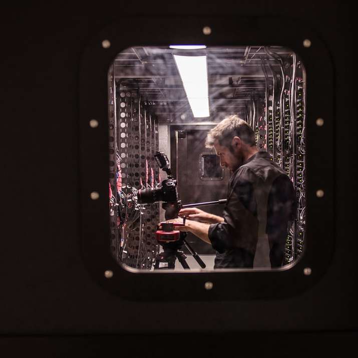 homem segurando uma câmera DSLR preta puzzle deslizante online