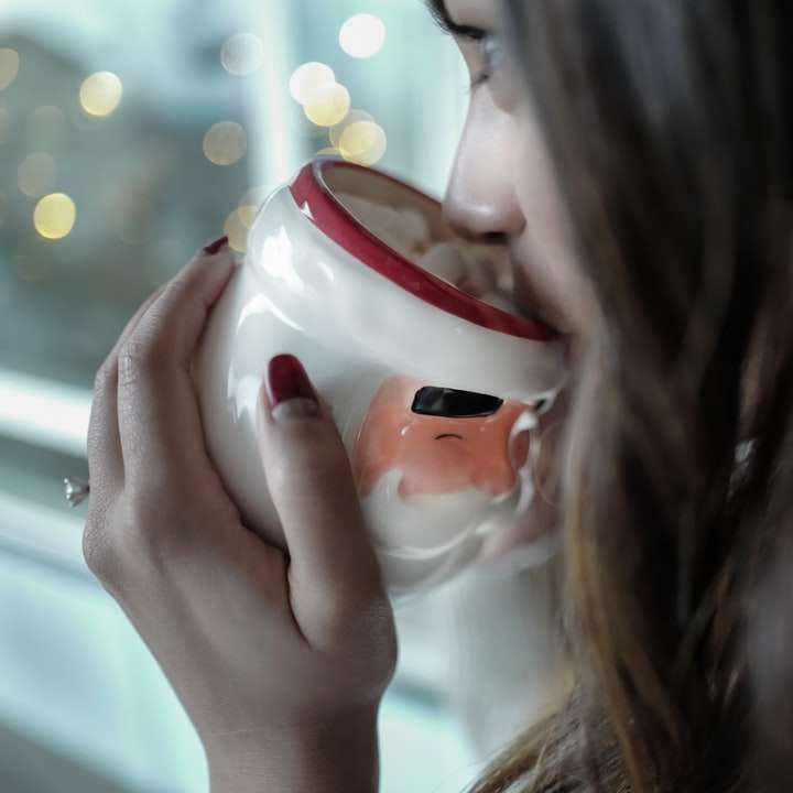 kvinna som dricker på vit och röd keramisk mugg Pussel online