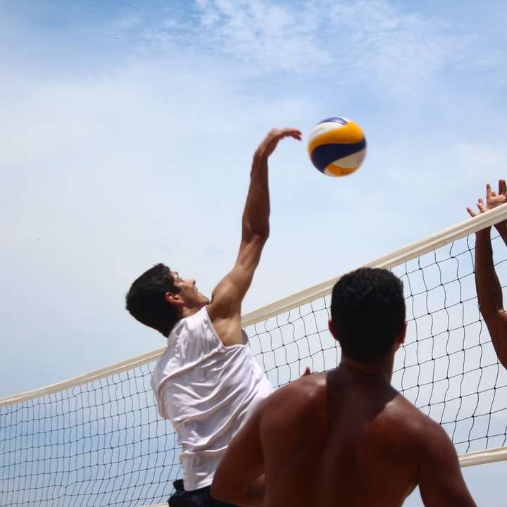 man in white shorts playing volleyball during daytime sliding puzzle online