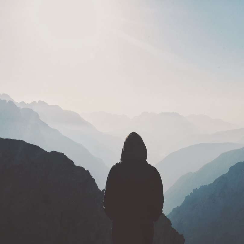 άντρας με κουκούλα στέκεται μπροστά από το βουνό online παζλ