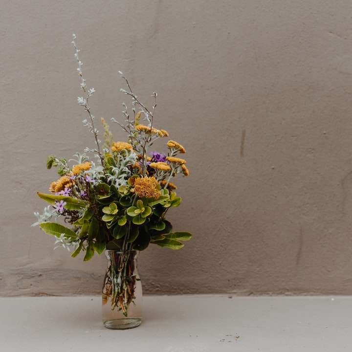żółte i białe kwiaty w wazonie z przezroczystego szkła puzzle online
