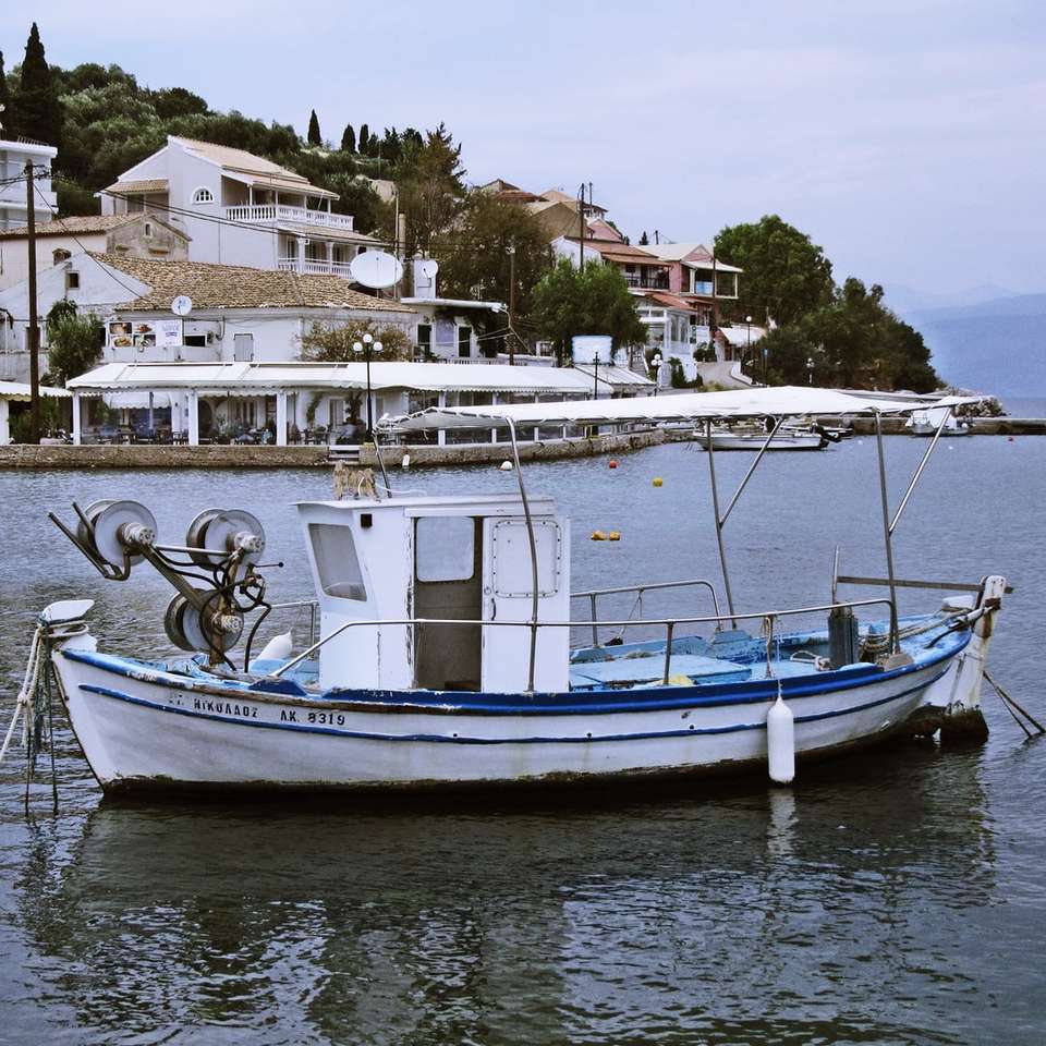 vit och blå båt på vatten under dagtid Pussel online