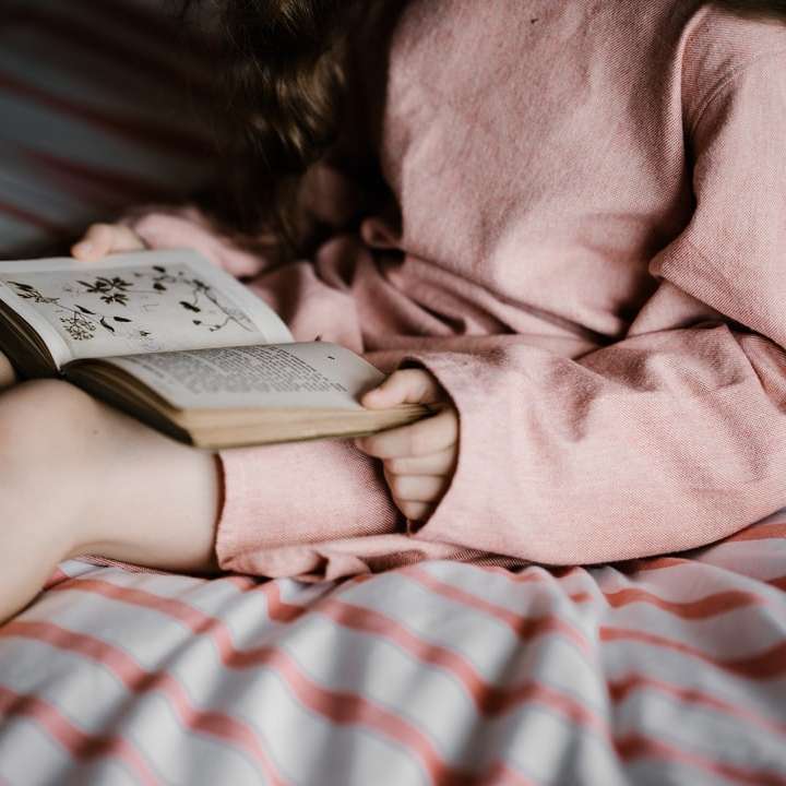 kobieta czyta książkę na białych i czerwonych tekstyliach puzzle online