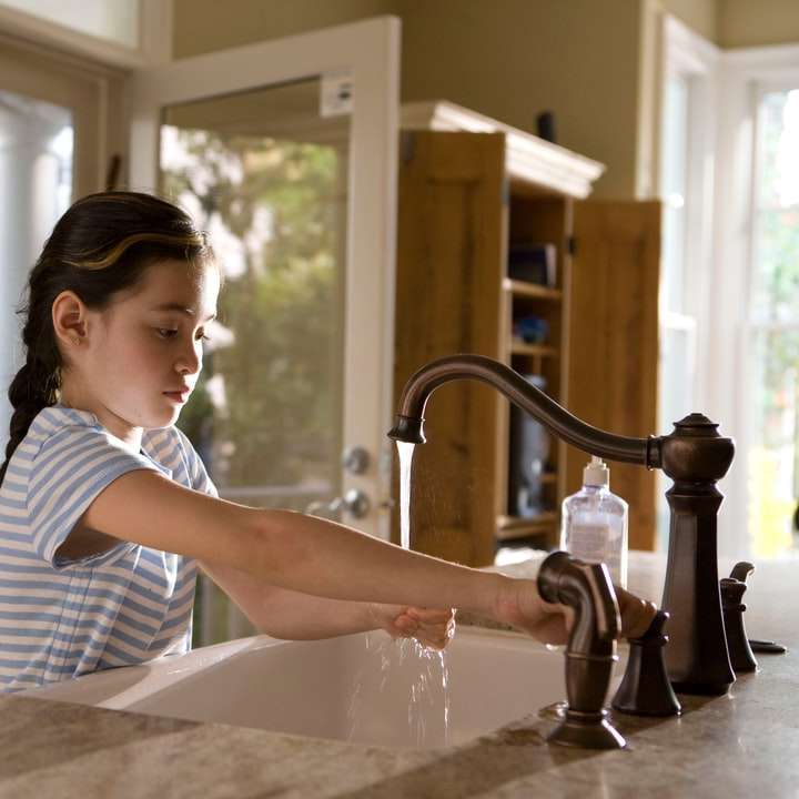 женщина в сине-белой полосатой рубашке моет руки онлайн-пазл
