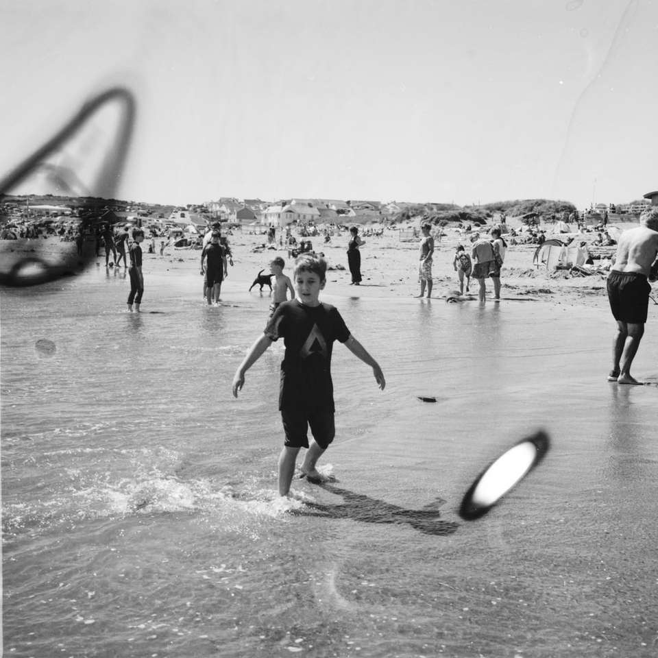 grayscale photo of people playing on beach sliding puzzle online